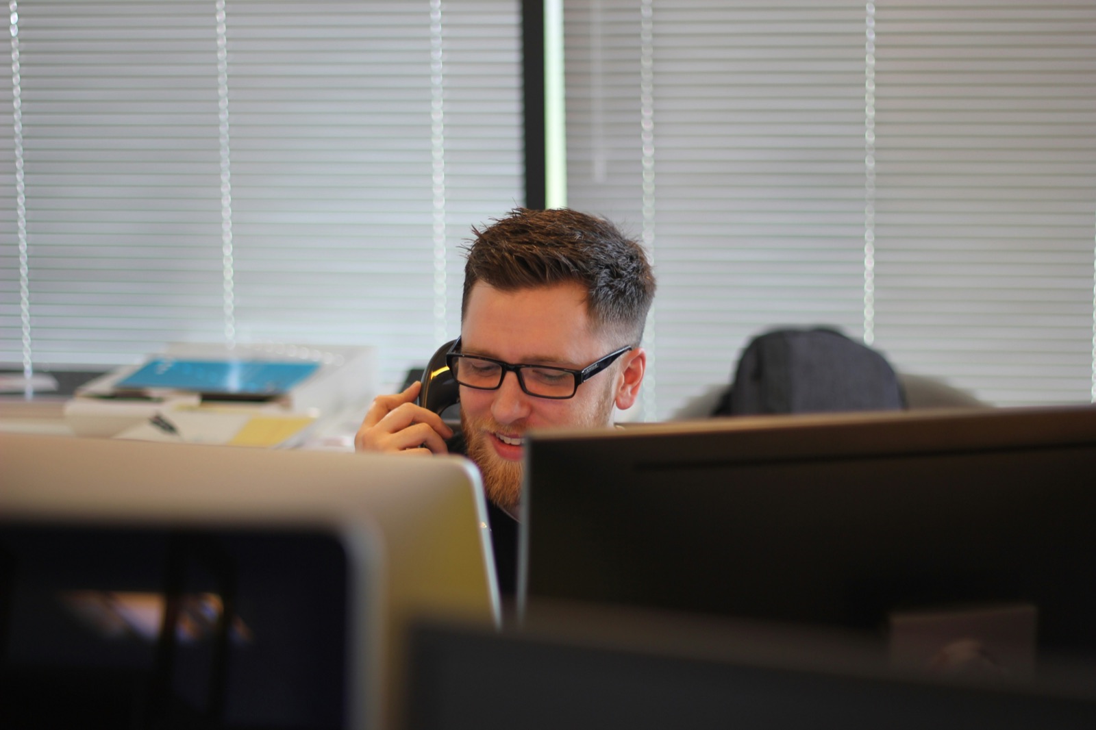 Persona sorridente al telefono durante una chiamata di qualifica del contatto